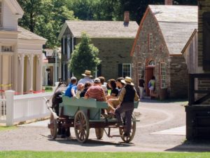 People on an old fashion cart at the Farmers' Museum