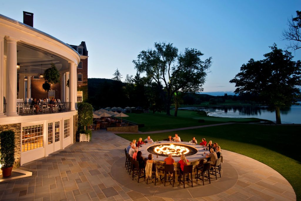 People relaxing around a fire outside Otesaga Resort