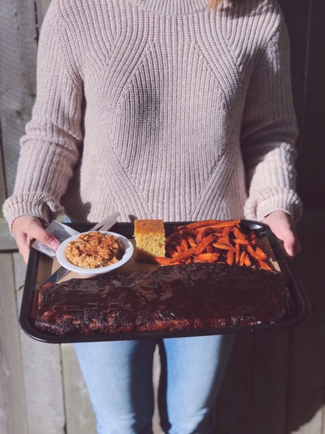 Woman holding tray of Ray Brothers famous BBQ ribs
