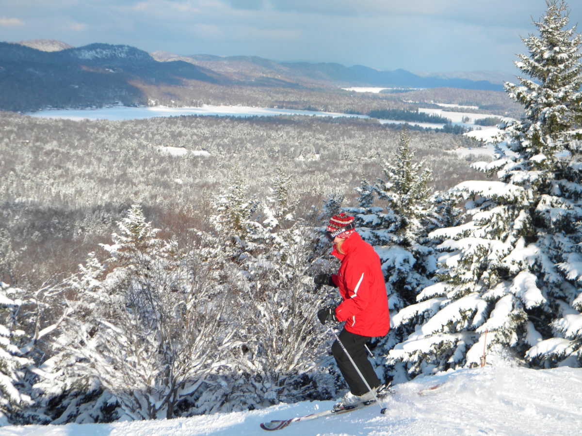 A skier on McCauley Mountain with a view of snowy mountains